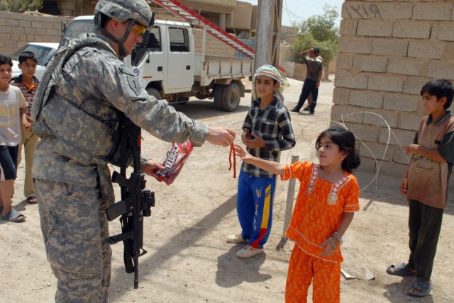 BAGHDAD - 1st Lt. Justin Casey, an Ogdensburg, N.Y. native, assigned to the Joint Projects Management Office, 2nd Brigade, 1st Infantry Division, gives candy to an Iraqi girl in the Nasir Wa Salam neighborhood here, June 25. While out on missions,...