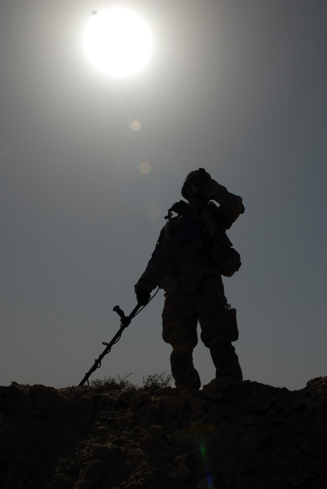 BAGHDAD - Pfc. Daniel Parker of Jacksonville, Fla., an infantryman assigned to Company D, 1st Combined Arms Battalion, 63rd Armored Regiment, 2nd Brigade Combat Team, 1st Infantry Division, endures the hot summer sun on a sand dune while searching fo...
