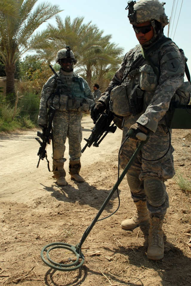BAGHDAD - Spc. Thomas Marcello of Honolulu, searches the ground beside a swamp near the Euphrates River for weapons caches during a joint search with the Iraqi Army. Marcello and Staff Sgt. Maurice Jones (left), of New Brockton, Ala., are both infant...