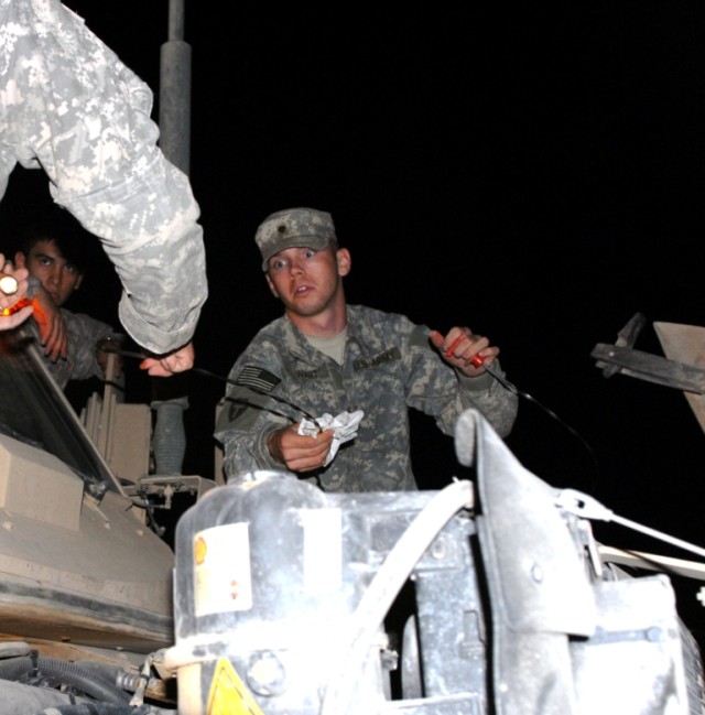 CAMP KOREAN VILLAGE, Iraq – Spc. Timothy Stewart, a vehicle driver serving with B Company, 2nd Battalion 142nd Infantry, 56th Infantry Brigade Combat Team, checks transmission fluid levels in his Mine Resistant Ambush Protected vehicle in the early m...