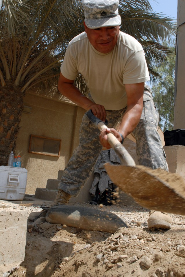 VICTORY BASE COMPLEX, Iraq - San Diego native, Sgt. Jose Guerrero, a light wheel mechanic assigned to E Company, 5th Battalion, 52nd Air Missile Defense Regiment, Multi-National Division - Baghdad, shovels dirt at the base of a flagpole here, June 26...