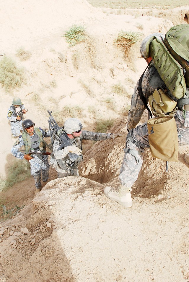MA'DAIN REGION, Iraq - Paratroopers assigned to K Troop, 5th Squadron, 73rd Cavalry, 82nd Airborne Division, Multi-National Division - Baghdad and National Police officers assigned to the 3rd NP Brigade, 1st NP Division cross a trench in order to rea...