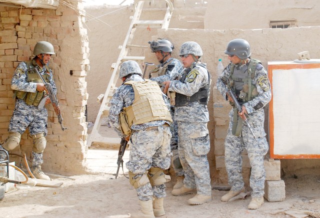 MA'DAIN REGION, Iraq - National Police officers, assigned to the 3rd NP Brigade, 1st NP Division, position themselves to enter a home in a small village, June 26, in the Ma'dain region, located outside of eastern Baghdad. Iraqi Security Forces and Pa...