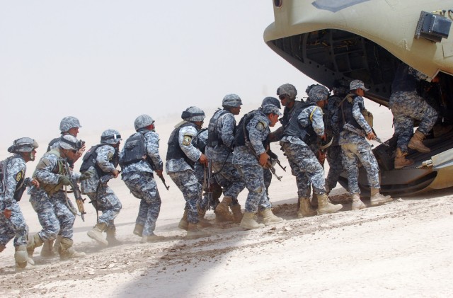 MA'DAIN REGION, Iraq - National Police officers assigned to the 3rd NP Brigade, 1st NP Division and Paratroopers assigned to K Troop, 5th Squadron, 73rd Cavalry, 82nd Airborne Division, Multi-National Division-Baghdad, load a CH-47 Chinook helicopter...