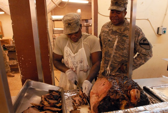 Staff Sgt. Nathan Sutherland (right) from Jamaica and Staff Sgt. George Crocker, Chesapeake, Va. native, both food service specialists with 1st Battalion, 8th Cavalry Regiment, 2nd Brigade Combat Team, 1st Cavalry Division, carve a roast prior to ser...