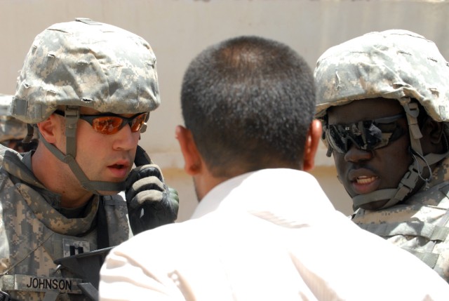 BAGHDAD - Capt. Kenneth Johnson, from Fort Riley, Kan., the brigade surgeon of 2nd Brigade, 1st Infantry Division, and an interpreter listens intently to contractor, Ahmed Husain Saood, as he explains the procedures taken to have running water...