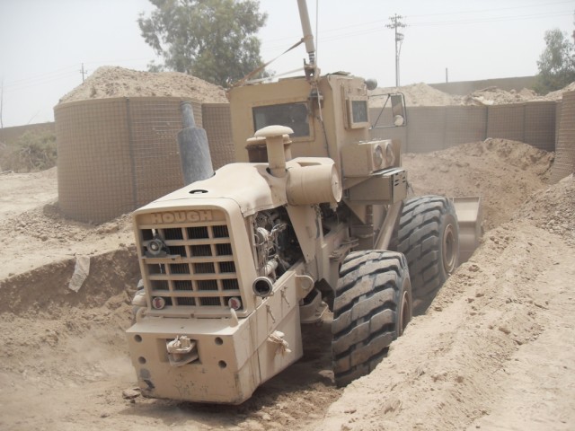 BAGHDAD - Pfc. Mario Quinones, heavy equipment operator, earth moving platoon, 46th Engineer Combat Battalion (Heavy), a native of Guayanilla, Puerto Rico, uses a bucket loader to dig a test fire pit June 28 at Rawandan Palace Complex here. Quinones ...