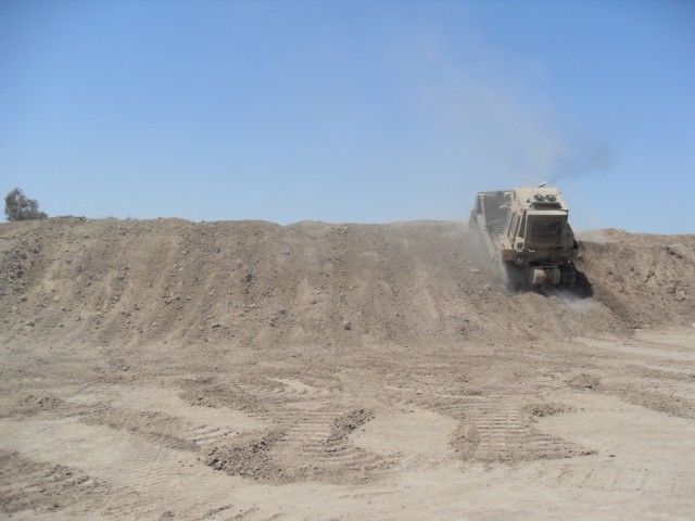 BAGHDAD - Pfc. David K. Branch, heavy equipment operator, 46th Engineer Combat Battalion (Heavy), 225th Engineer Brigade, a native of Gulf Port, Mississippi uses a large bulldozer to straighten out a 20-foot berm.  A berm is an earthen wall used in f...