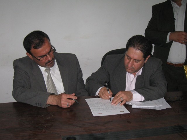 BAGHDAD - Sameer al Haddad (left), the receivership secretariat for the Government of Iraq, and Dr. Mahdi al-Kaisey, deputy minister for the Ministry of Agriculture sign documents returning the facility formerly known as Joint Security Station...
