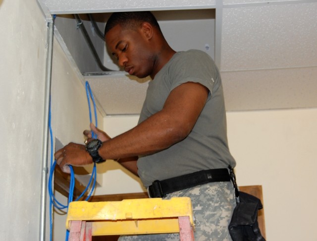 BAGHDAD - Spc. George Hester, a network help desk representative of the 30th Brigade Special Troops Battalion, 30th Heavy Brigade Combat Team, rewires computer and phone lines at a building on Forward Operating Base Falcon, July 1. Hester, a...
