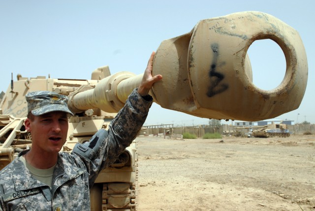 TAJI, Iraq - Maj. Matthew DeLoia, an artillery officer from Duluth, Minn., shows off one of dozens of abandoned howitzers July 2, which are being refurbished for use by the Iraqi Army at Camp Taji, which is north of Baghdad. DeLoia is a member of a M...