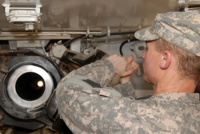 TAJI, Iraq - Maj. Matthew DeLoia, an artillery officer assigned as a Military Transition Team advisor to the 34th Armored Brigade, 9th Iraqi Army Division, examines the breech end of a firing tube on a M109A1 howitzer at Camp Taji. The howitzer was o...