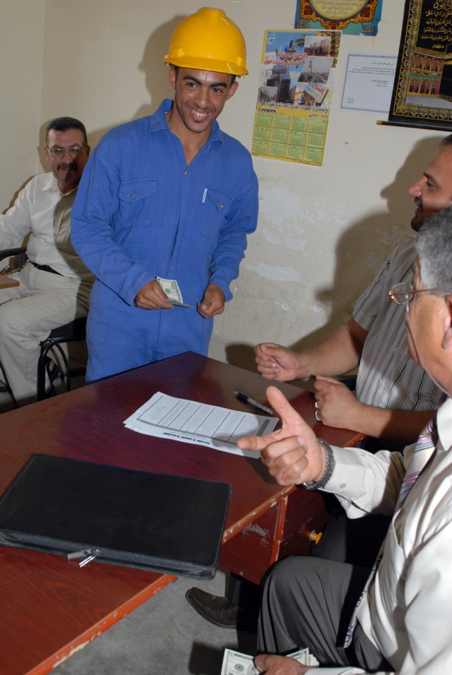 BAGHDAD - A newly certified electrical line refurbishment team member receives his pay in the Nasir Wa Salam district here, June 25. Though the students of the course recently graduated, they have been performing their duties as electrical repairmen ...