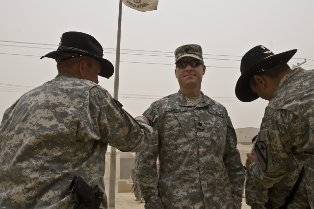 TAJI, Iraq - Col. Douglas Gabram (left), of Cleveland, Ohio, commander of the 1st Air Cavalry Brigade, 1st Cavalry Division, Multi-National Division - Baghdad, places a 1st Cav. Div. patch on the right shoulder of Lt. Col. Dean Keck (center), of...