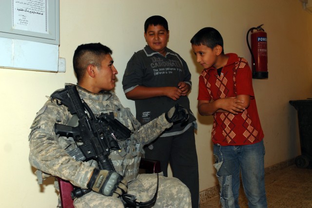 BAGHDAD - Cpl. Billy Burgess chats with Iraqi children at the new Tarmiyah Police Station, here, July 3. Burgess, from Lawton, Okla., is a military policeman assigned to the 591st Military Police Company, 93rd Military Police Battalion, 8th...