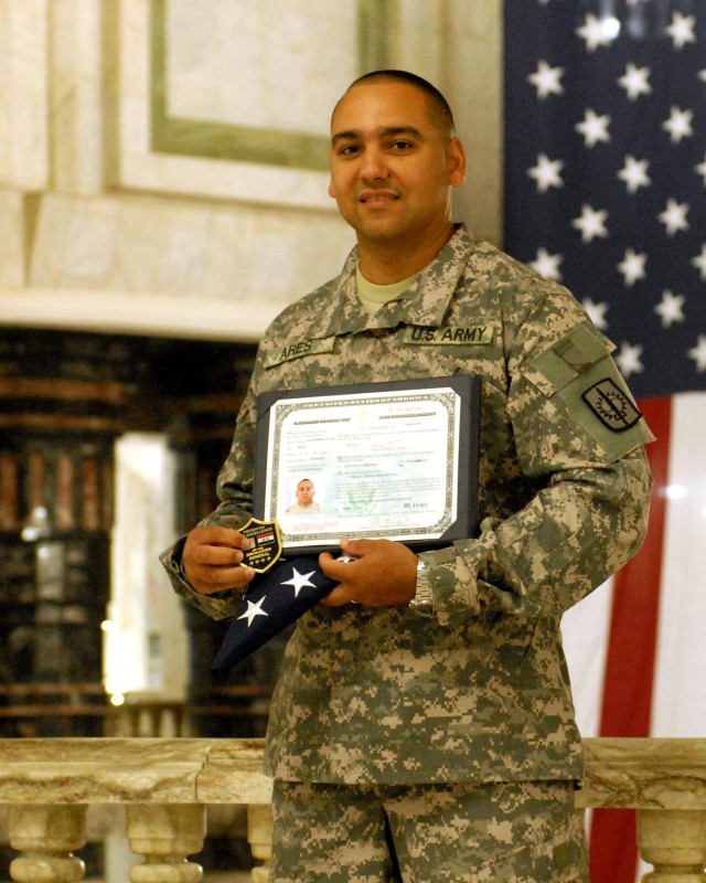 BAGHDAD - In the forefront of the flag that has welcomed millions from around the world, Spc. Benny Ares, an 8th Military Police "Watchdog" Brigade Soldier, proudly displays his United States citizenship certificate and memorabilia after joining...