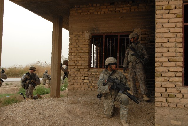 AL FARIS, Iraq - During a patrol in March, Sgt. Oshea Washington (kneeling, right) of Easton, Pa., a Soldier with Company C, 1st Battalion, 111th Infantry, 56th Stryker Brigade Combat Team, takes up a position at the corner of a building along with o...