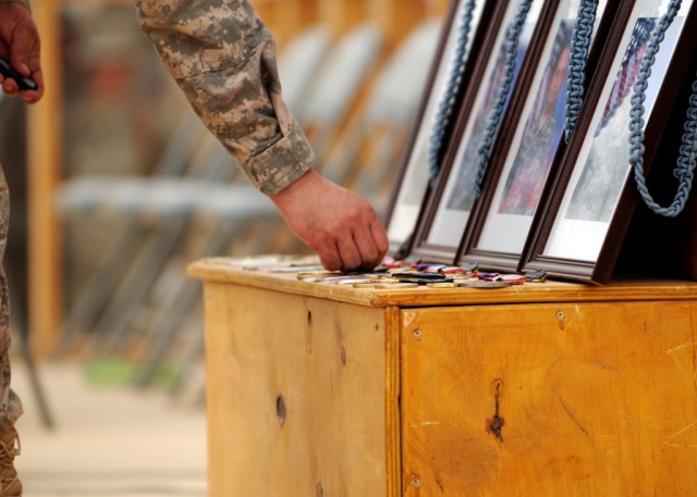 MAHMUDIYAH, Iraq - Brigade Sgt. Maj. John Swart, places a 30th Heavy Brigade Combat Team unit patch by the photo of Sgt. 1st Class Edward Kramer, Sgt. Juan Baldeosingh, Sgt. Roger Adams Jr. and Spc. Robert Bittiker, during a memorial service held in ...