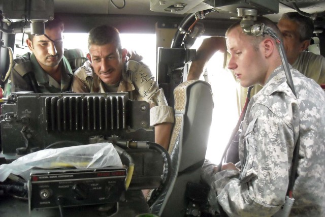 Spc. Anthony Wilson from Mosheim Tenn., with 3rd Battalion, 8th Cavalry Regiment, 3rd Heavy Brigade Combat Team "Greywolf," 1st Cavalry Division instructs two Soldiers with the 6th Brigade, 2nd Iraqi Army Division on their new single channel...