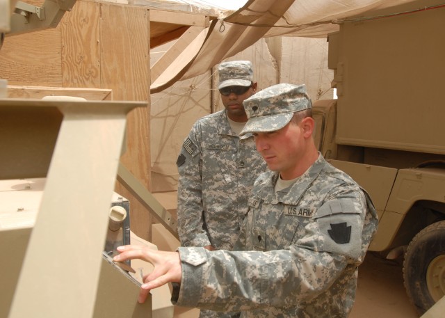 TAJI, Iraq - Spc. Ryan David (at right) and Staff Sgt. Keith McBroom, both of Pittsburgh and both with 1st Platoon, 656th Signal Company, 56th Stryker Brigade Combat Team, power up a satellite transmission terminal generator July 10 at Camp Taji,...
