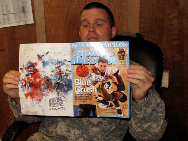 BAGHDAD -  Oxford, N.C. native, Maj. Robert "Bert" Kemp III relaxes while reading his Sports Illustrated magazine commemorating the University of North Carolina - Chapel Hill's NCAA Basketball Tournament victory in his office at Forward Operating Bas...