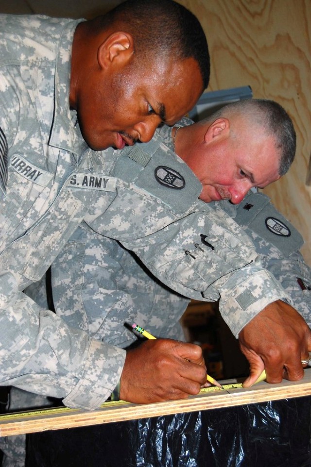 BAGHDAD - Staff Sgt. Frederick Murray, of Rose Hill N.C., and Staff Sgt. Vernon Hayes, of Lexington, N.C., mark measurements to cut support braces for a desk in the logistics office on Forward Operating Base Falcon, July 13. Murray, the headquarters ...