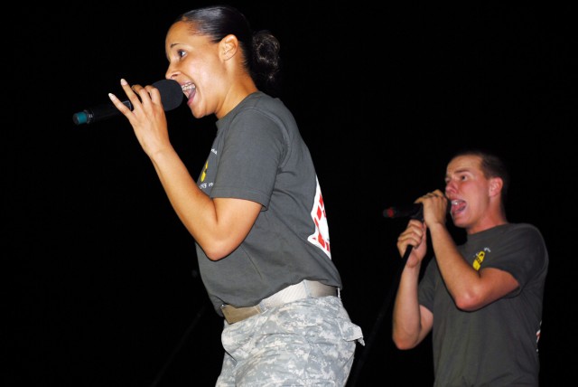 BAGHDAD - Bemidji, Minn. native, Staff Sgt. Renatta Draper (left), a vocalist, enthusiastically sings for a crowd at Camp Liberty, here, July 16, as Spc. Chris Rettig (right), a tuba player and vocalist from Defiance, Ohio, provides backup vocals...