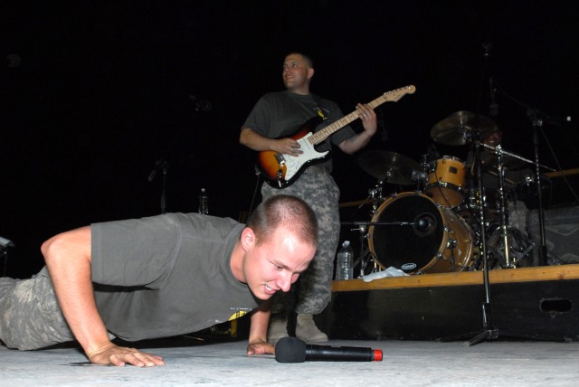 BAGHDAD - After poking fun at his noncommissioned officers during a rendition of a Rage Against the Machine song, Spc. Chris Rettig (foreground), a tuba player and vocalist from Defiance, Ohio, does push-ups on stage as Sgt. Jason Smelser, from...