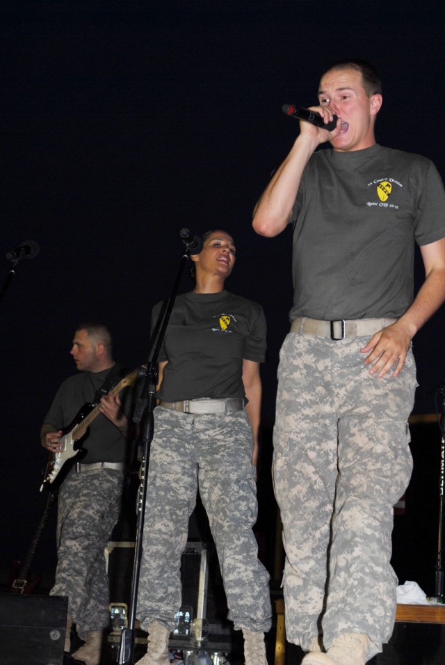 BAGHDAD - Spc. Chris Rettig (right), a tuba player and vocalist from Defiance, Ohio, belts out lyrics at a rock show at Camp Liberty, here, July 16, while Staff Sgt. Renatta Draper (center) a vocalist from Bemidji, Minn., sings back up and Sgt....