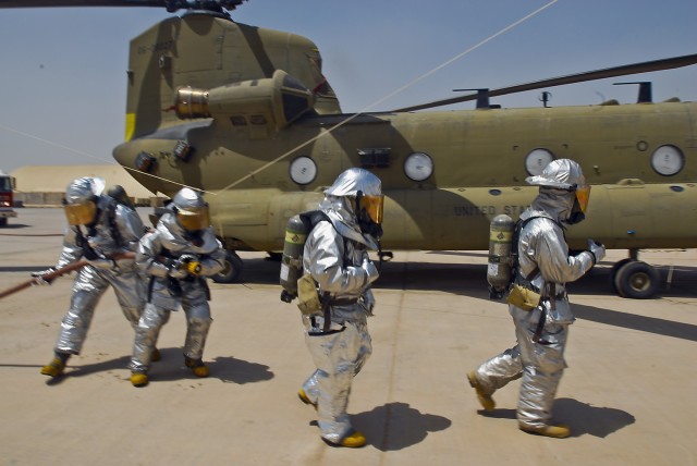 TAJI, Iraq- Fully suited firefighters from the Taji fire department move quickly to shut down vital systems on a CH-47F Chinook helicopter so they can battle a mock fire, July 17,  at Camp Taji, Iraq.  This was part of a training exercise held by...
