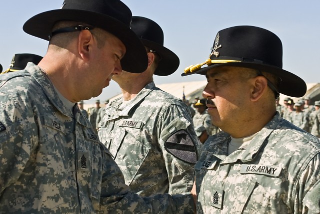 TAJI, Iraq - Command Sgt. Maj. Glen Vela (left) from Dallas, the command sergeant major of the 1st Air Cavalry Brigade, 1st Cavalry Division, Multi-National Division - Baghdad, slaps a 'First Team' combat patch on Command Sgt. Maj. Jose Soilz (right)...