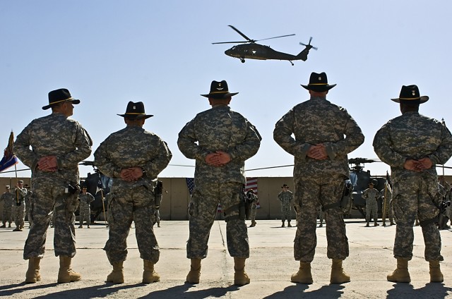 Command sergeants major, past and present, of the 1st Air Cavalry Brigade, 1st Cavalry Division, Multi-National Division - Baghdad, stand and watch as a UH-60 Black Hawk helicopter from the 1st ACB flies over during their change of responsibility cer...