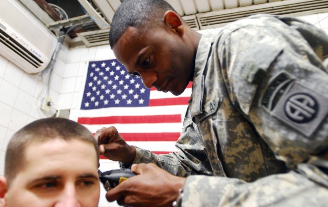 Sgt. Teo Garcia prepares to cut a Soldier's hair July 20, at Joint Security Station Loyalty, Iraq, located in the 9 Nissan district of eastern Baghdad. Garcia says cutting hair relaxes him even during the most stressful of times during his deployment...