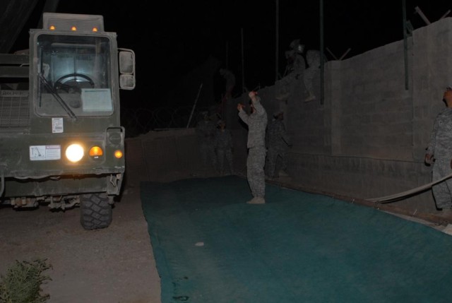 BAGHDAD - A Soldier with the 277th Engineer Company, 46th Engineer Combat Battalion (Heavy), 225th Engineer Brigade, provides ground guidance to the driver of a military crane truck during night operations at Joint Security Station Zafaraniya July 18...