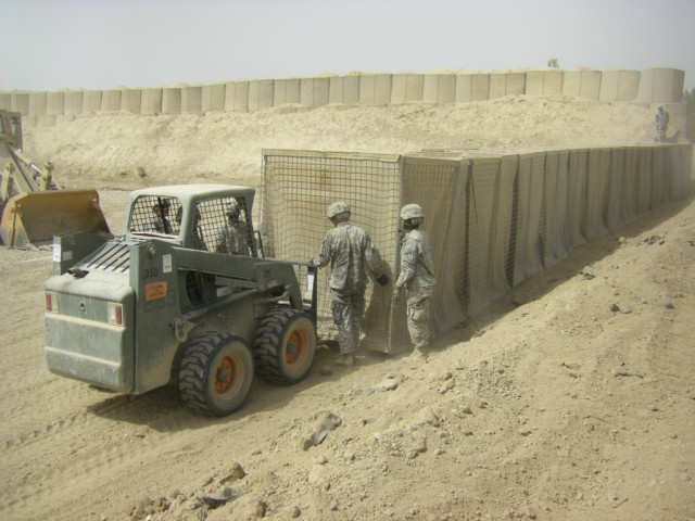 BAGHDAD - Soldiers of earthmoving platoon, 46th Engineer Combat Battalion (Heavy), 225th Engineer Brigade, use a Bobcat loader to set up HESCO barriers, large containers filled with dirt used for force protection, during their range construction proj...