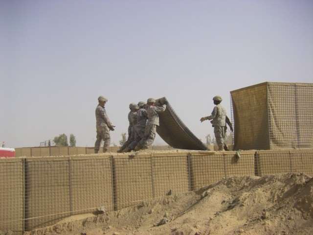 BAGHDAD - Soldiers of Company B, 46th Engineer Combat Battalion (Heavy), 225th Engineer Brigade, lift an empty HESCO barrier into place to create the second tier of the range separation wall July 19 at Task Force Raptor here.  The wall will protect S...