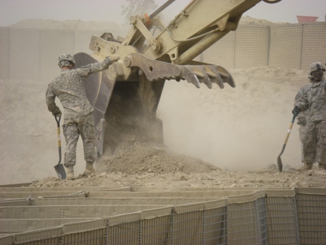 BAGHDAD - Pvt. Gary McFadden of London, Ky., heavy equipment operator, 
46th Engineer Combat Battalion (Heavy), 225th Engineer Brigade, ground guides 
the hydraulic excavator operator driven by Spc. Mark Dillon of Reed City, Mich., as he fills HESCO ...