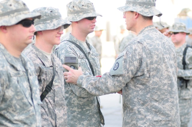 BAGHDAD - Spc. Charles Clements, of Gastonia, N.C., receives the brigade combat patch from Brigade Commander Col. Greg Lusk as fellow Company C, 252nd Combined Arms Battalion, 30th Heavy Brigade Combat Team Soldiers Pfc. Jeremy Hester, of...