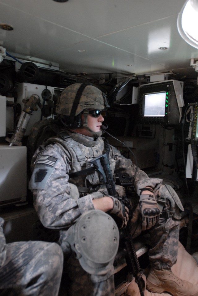 TAJI, Iraq - Spc. Elliott Smith of Reading, Pa., a Soldier with A Troop, 2nd Squadron, 104th Cavalry Regiment, 56th Stryker Brigade Combat Team, talks on a radio headset in a Stryker vehicle July 20. The eight-wheeled Stryker vehicle is fielded in...