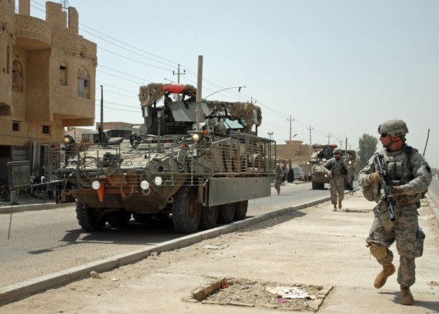 CAMP TAJI, Iraq - Staff Sgt. Andrew Frengel of Lebanon, Pa., other Soldiers and Stryker vehicles of A Troop, 2nd Squadron, 104th Cavalry Regiment, 56th Stryker Brigade Combat Team move through Sab al Bour, southwest of Taji, July 20. Pennsylvania...