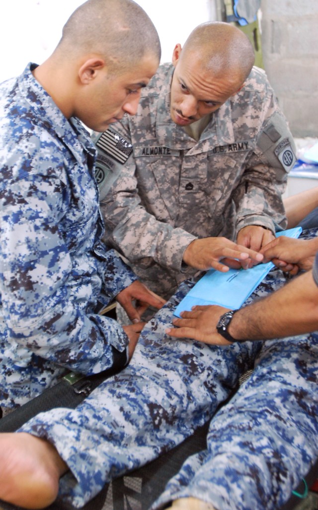 BAGHDAD - Sgt. 1st Class Juan Almonte, a New York City native, shows a National Police medic how to properly insert a needle on a patient during a combat medic training exercise July 22 at Joint Security Station Loyalty, located in the 9 Nissan...