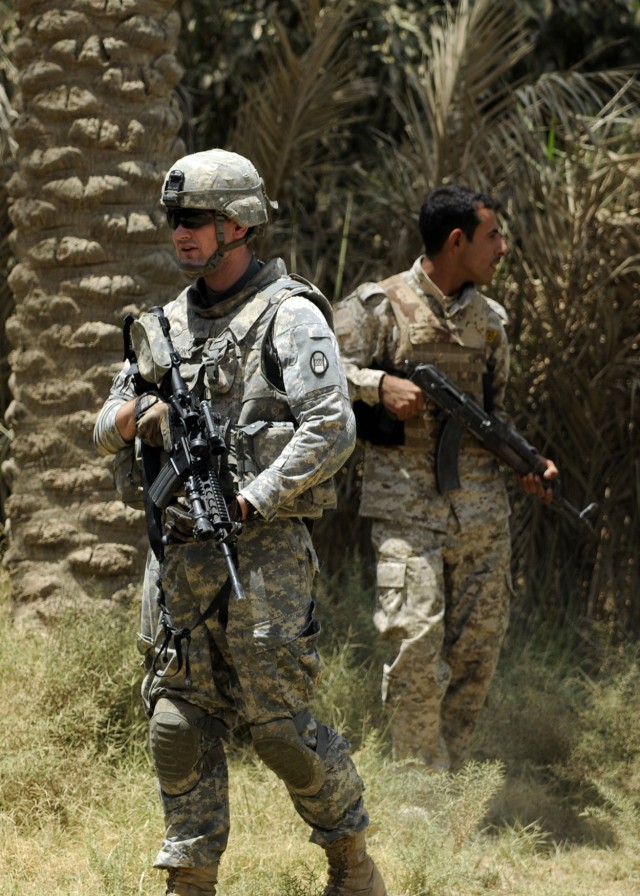 ADWANIYAH, Iraq - Sgt. Jonathan Hinson, Battery B, 1st Battalion, 113th Field Artillery Regiment, 30th Heavy Brigade Combat Team, of Charlotte, N.C.,(left), and an Iraqi Army soldier, secure the perimeter of a home, south of Baghdad, while on a...