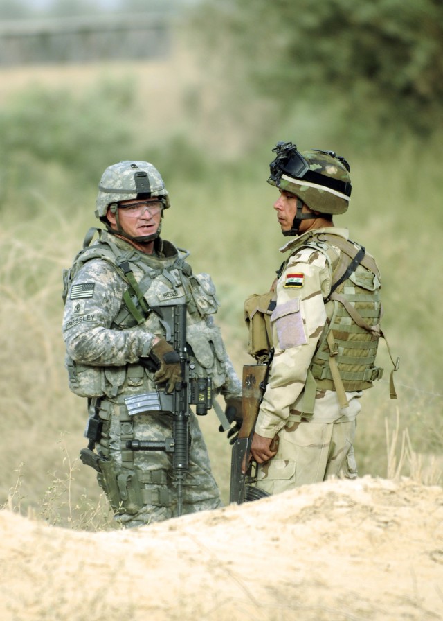 ADWANIYAH, Iraq - First Sgt. Phillip Pressley, Battery B, 1st Battalion, 113th Field Artillery Regiment, 30th Heavy Brigade Combat Team, of Monroe, N.C., talks with an Iraqi Army soldier while on a joint patrol, south of Baghdad, June 20. The...