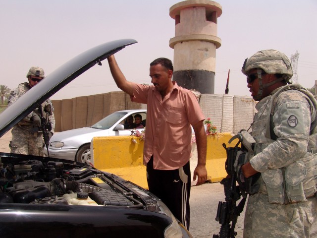 MAHMUDIYAH, Iraq -- An Iraqi man holds up his car hood up as Sgt. Jefery Fyke (left), a humvee driver from Fayetteville, N.C, and Spc. Ivie Dixon, an armored vehicle crewman from Baltimore, both with Company B, 120th Combined Arms Battalion, 30th Hea...