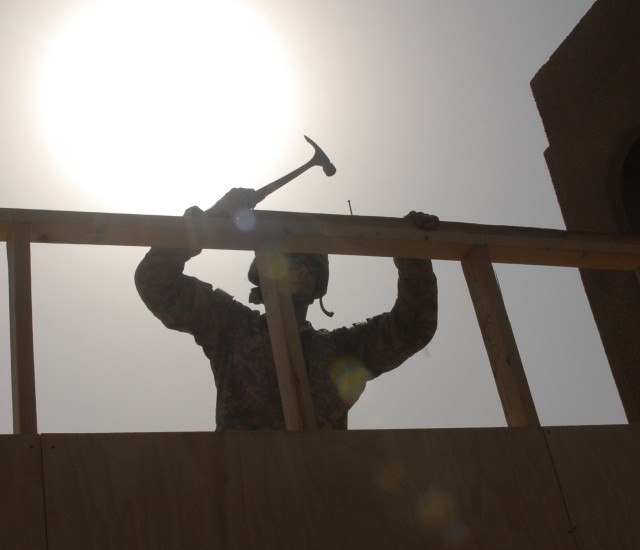 BAGHDAD - Wausau, Wis. native, Spc. Mathew Gutowski, a carpenter with the 46th Engineer Battalion, 225th Engineer Brigade, braves the heat while driving nails into a double top plate that will support walls for a brand new dining facility at...