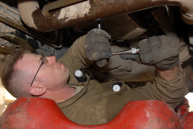 BAGHDAD - Spc. Thomas Parker loosens a bolt to drain transmission fluid from a humvee in the Division Special Troops Battalion motor pool, here, July 24. Parker, who is assigned to Headquarters Support Company, DSTB, 1st Cavalry Division at Camp...