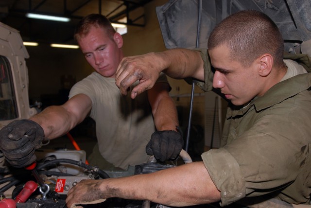 BAGHDAD - Spc. Phillip Corbin of Braidwood, Ill., and Pfc. Rick Hensler of Pontiac, Mich., install a new 400 amp generator in a humvee in the Division Special Troops Battalion motor pool, at Camp Liberty here July 24. The 400 amp generators are...