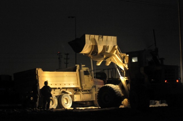 BAGHDAD - A bucket loader operator dumps concrete rubble and metal into the back of a 20-ton dump truck as Spc. Derek Fay, 46th Engineer Combat Battalion (Heavy), from Miami, Okla., oversees ground operations.  Fay provided ground guidance to ensure ...