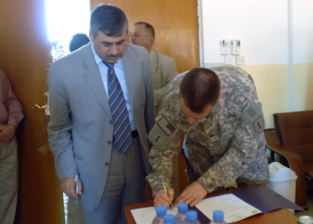 BAGHDAD - Lt. Col. Christopher Beckert, a native of Madison, Conn., deputy commanding officer, 2nd Heavy Brigade Combat Team, 1st Infantry Division, Multi-National Division - Baghdad, signs the official paperwork allowing the Mobile Rural Support Tea...
