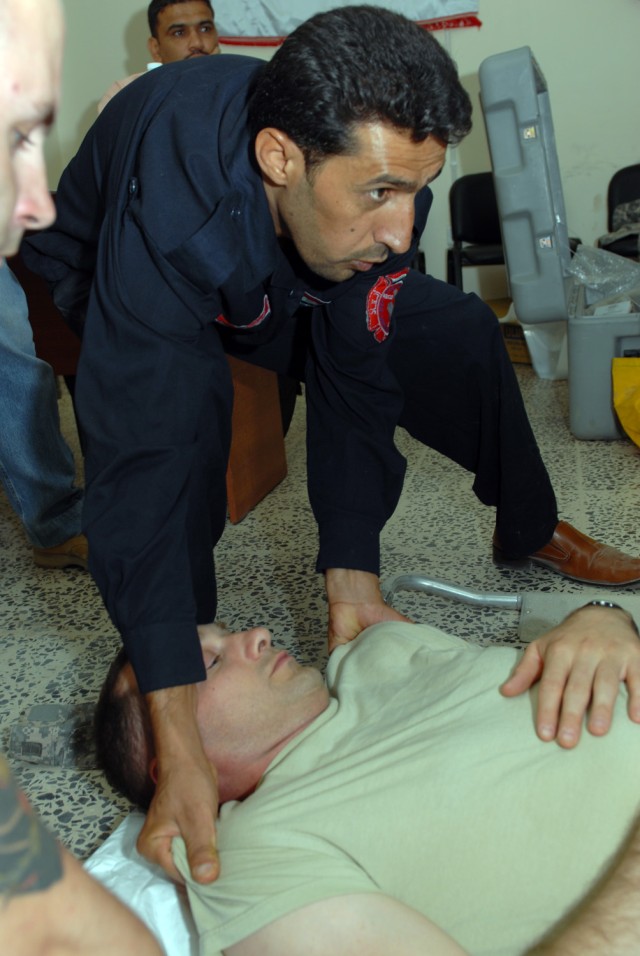 BAGHDAD - Salam Abdulla Mussin, an Iraqi firefighter, prepares to move Sgt. Michael Kuca as part of training to decontaminate a firefighter who has come into contact with hazardous materials at the Iraqi Civil Defense Directorate, here, July 26....